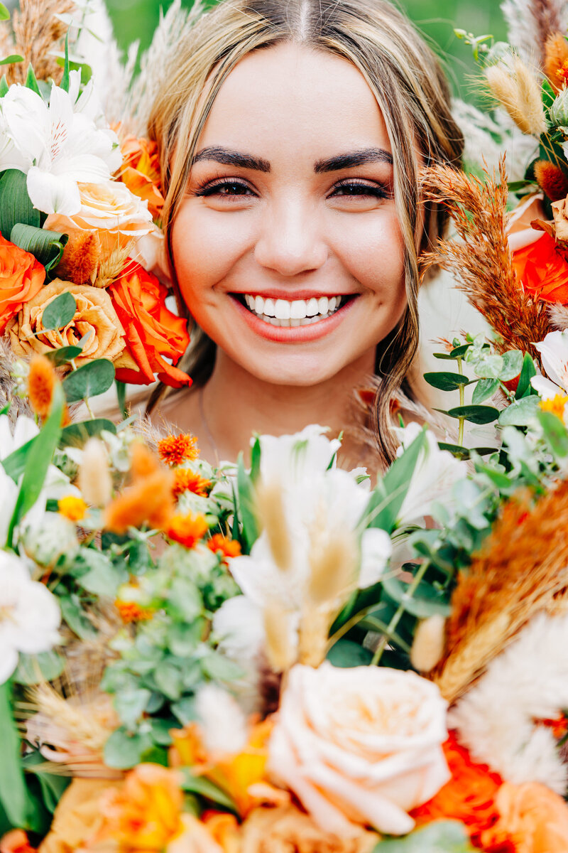 Close up photo of bride smiling and surrounded by flower bouquets at Shades of Green Events, Helena, MT