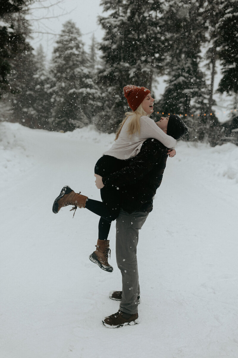 Couple picking one another up in the snow.