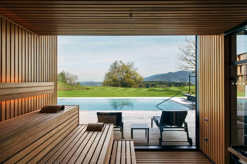 Landscape photo of a sauna with a pool in the background.