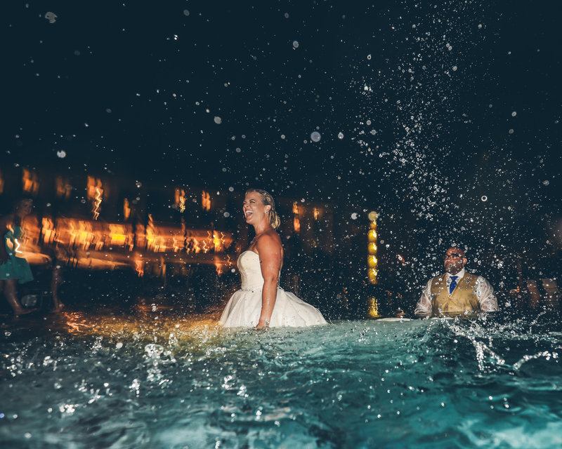 Asheville Photographer,  Light Shifter Studios captures a bride and groom jump into a pool after their Hawaii beach wedding. 