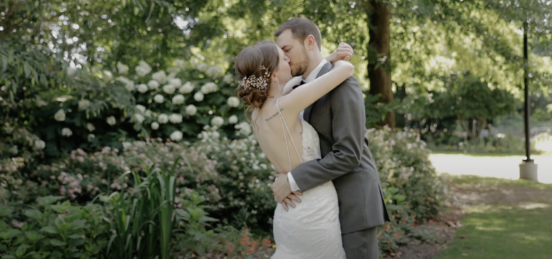 Dyersville Wedding Videographer Husband kisses wife  in green garden