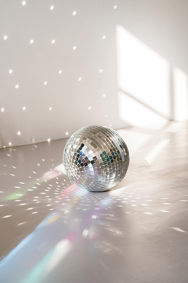 Photo of a Mirror Ball in a studio with the lights hitting it and shinning onto the walls.