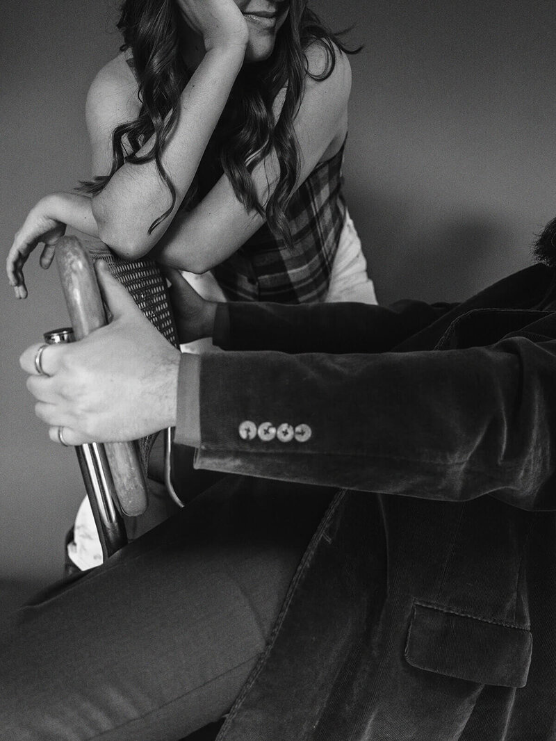 Black and white image faceless couple with arms resting on a chair.