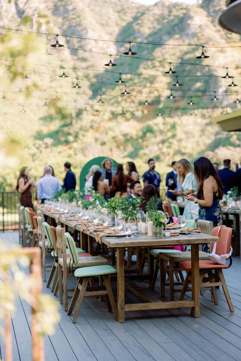outdoor wedding welcome dinner on a porch outdoors with a long table and fairy lights