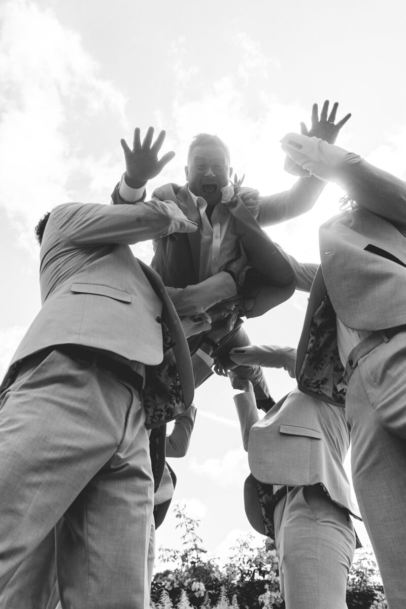 Groom gets thrown into the air during his groomsmen portraits at Hatch House