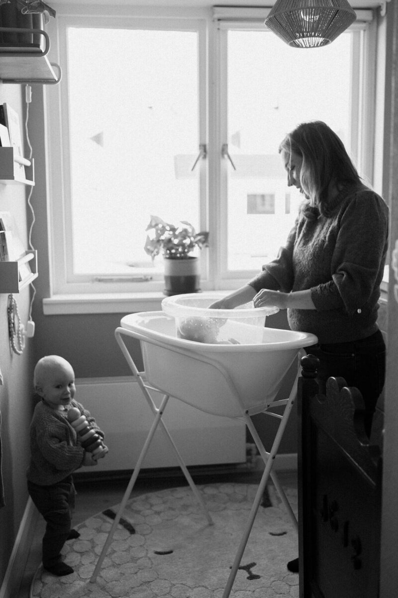 Mama wast pasgeboren baby met zoontje erbij tijdens gezin fotoshoot