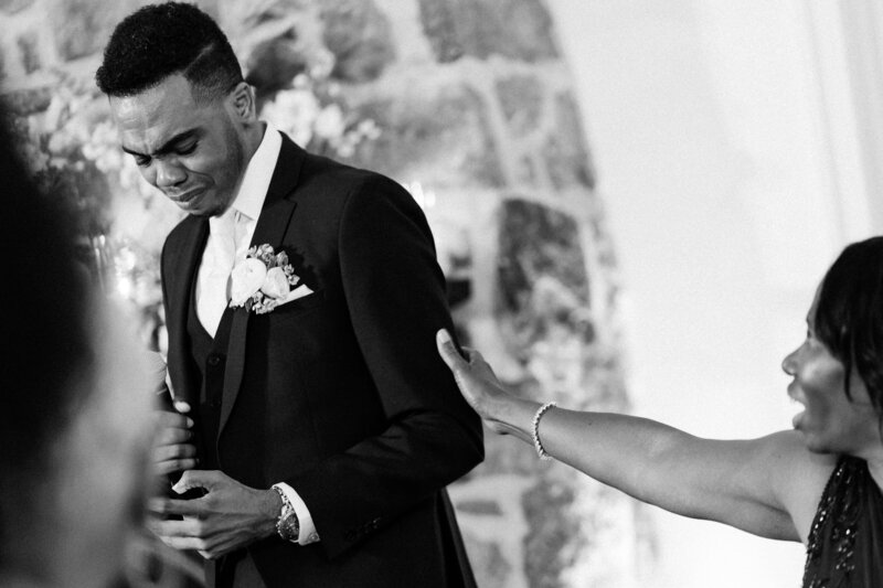 Groom laughs with bride during toasts at Glen Foerd Estate in Philadelphia, PA