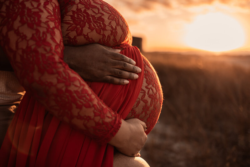 pregnant women showing her glowing belly as the sun is setting in the background