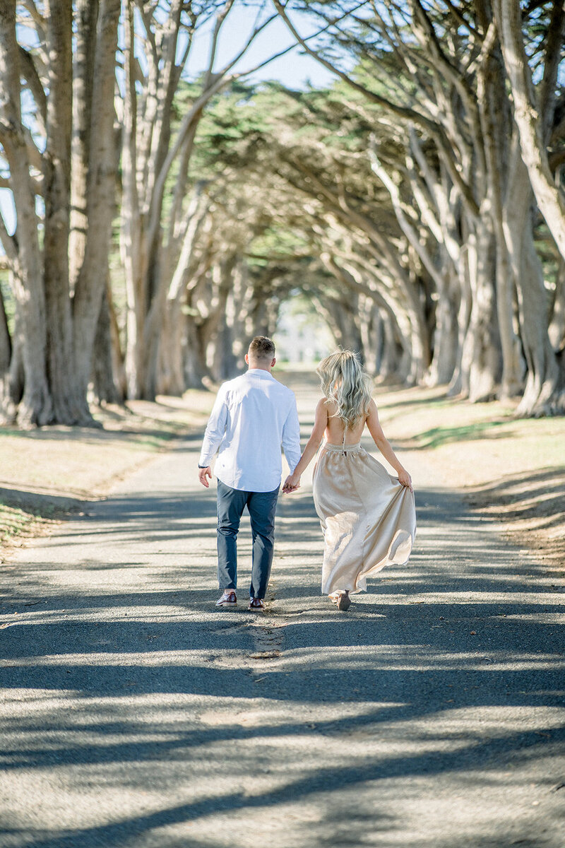 A couple enjoys a romantic walk at the picturesque Cypress Tree Tunnel in Point Reyes, California, photographed by Tiffany Longeway Photography.