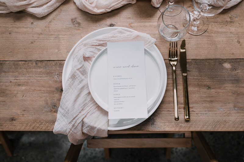Styling van servies met gouden bestek op een houten tafel.