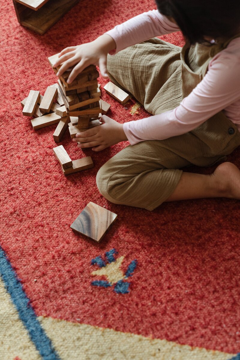 une enfant qui construit une tour en bois