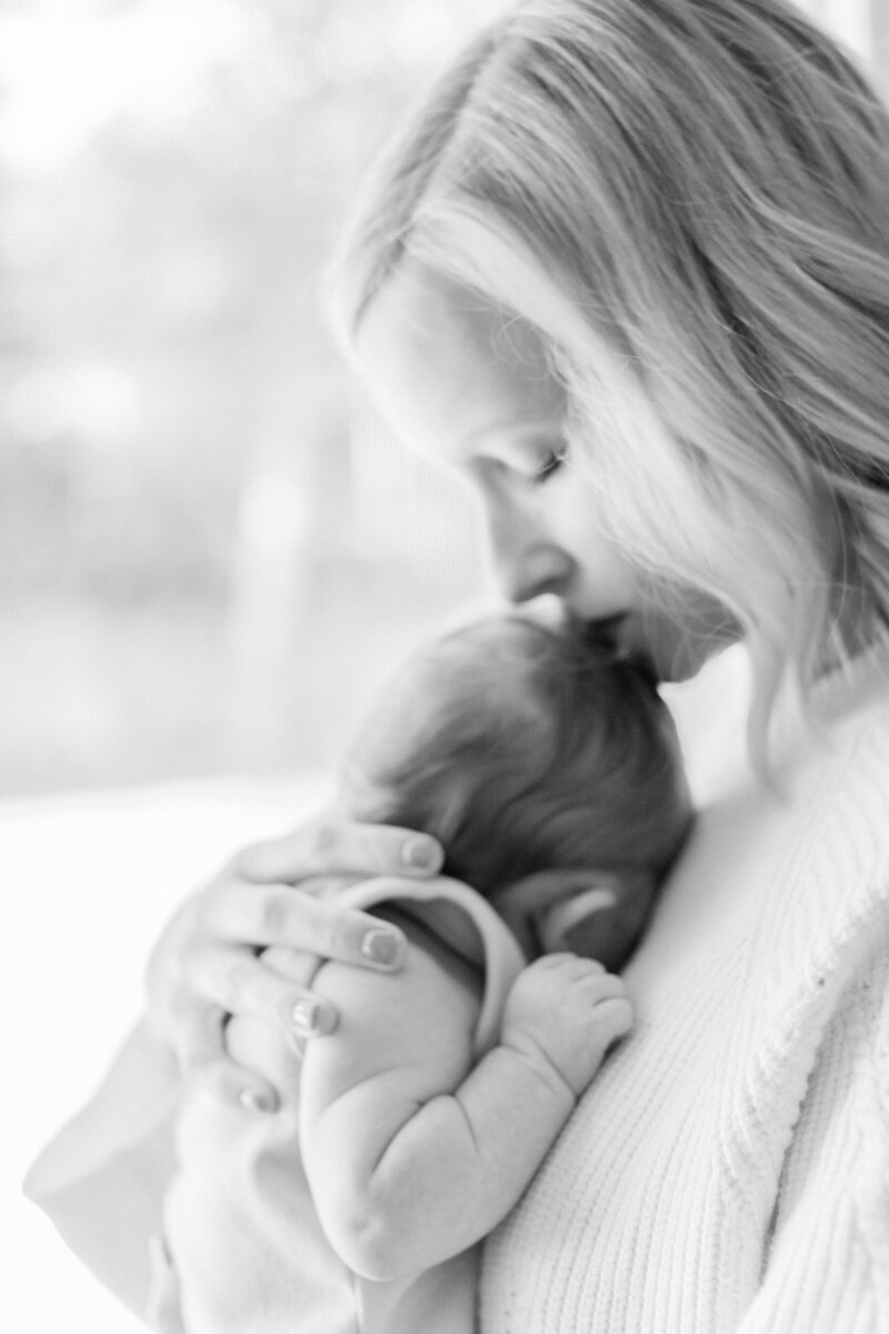 mother kissing her newborn by Orlando in-home newborn photographer