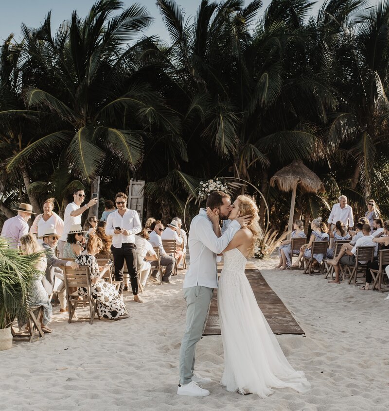 Capturez l'amour au Mexique : un couple s'embrassant après la cérémonie sur la plage, dans un cadre sublime de beauté naturelle et de design époustouflant.