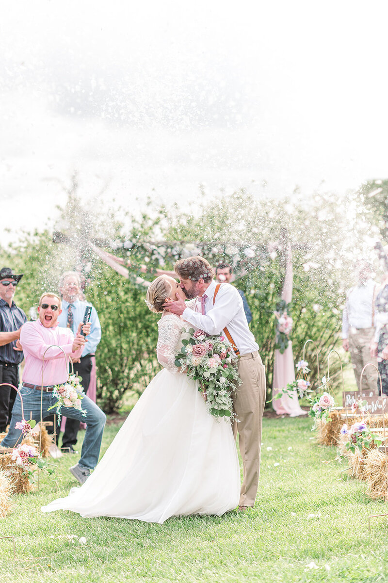 bride and groom kissing and wedding guests shot confetti into the air by york and lancaster photographer