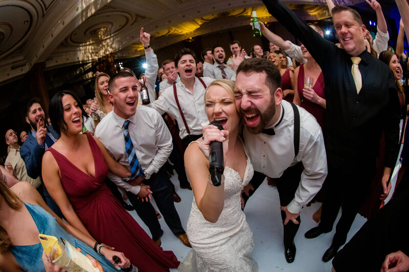 Bride and groom belting out music during their wedding reception at the Crystal Tea Room in Philadelphia, capturing their lively energy.