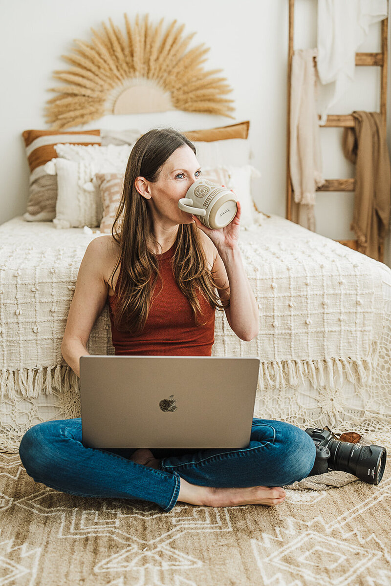 photographer in boston studio drinks coffee and works on laptop during brand photo session