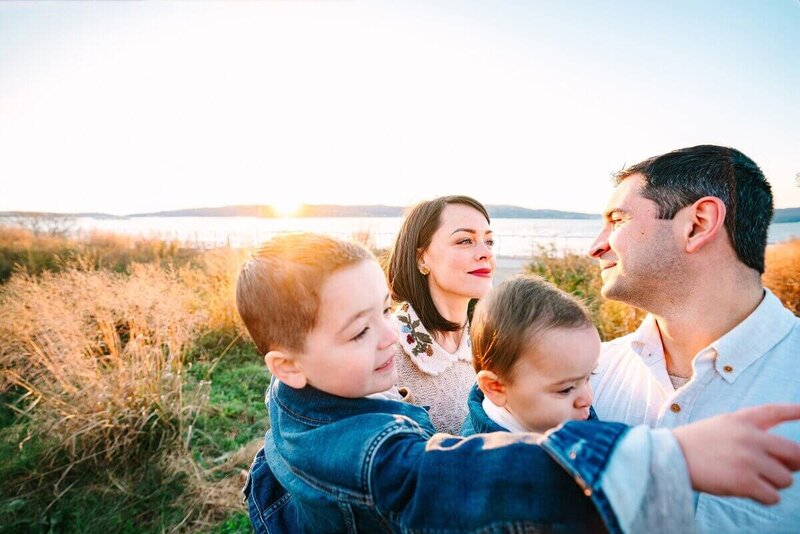 family enjoys a serene sunset in Hudson Valley, NY, with the Hudson river in the backdrop.