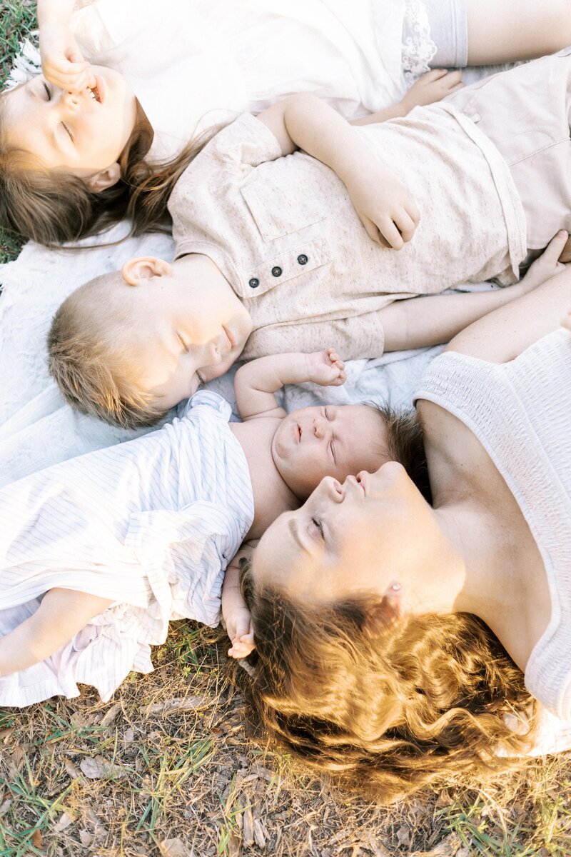 mom laying with her babies on a blanket during baby photos in peoria, illinois 