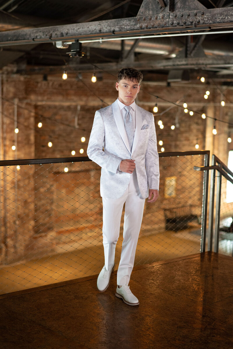 Groom wearing white suite standing in Indoor wedding venue