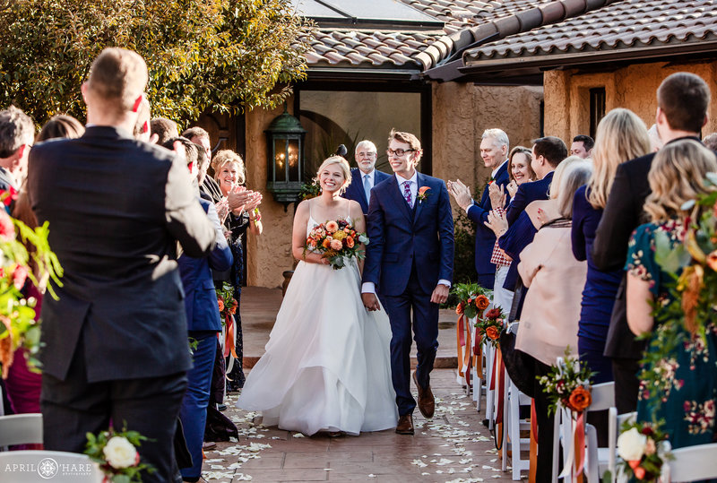Bride and groom walk down aisle at their fall courtyard wedding ceremony at Villa Parker