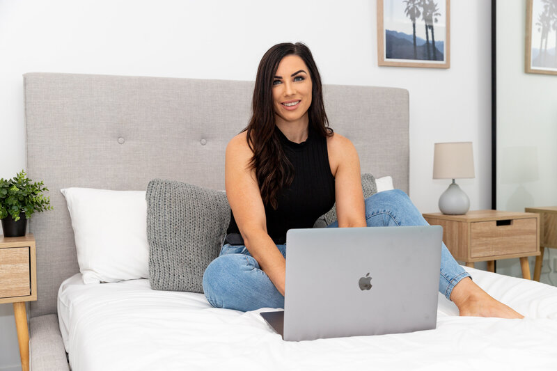 Woman sitting on a bed with a laptop