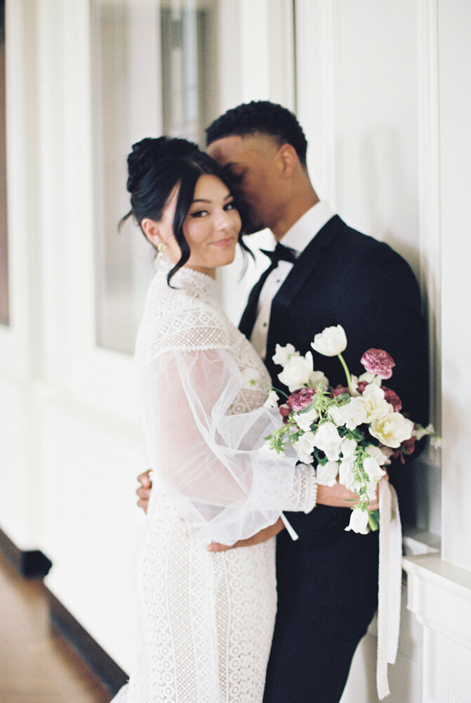 bride and groom snuggling with flowers