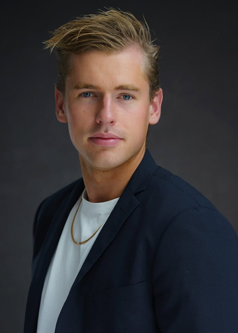 Professional headshot of a male model in San Francisco wearing a dark jacket, white t-shirt, and a gold chain