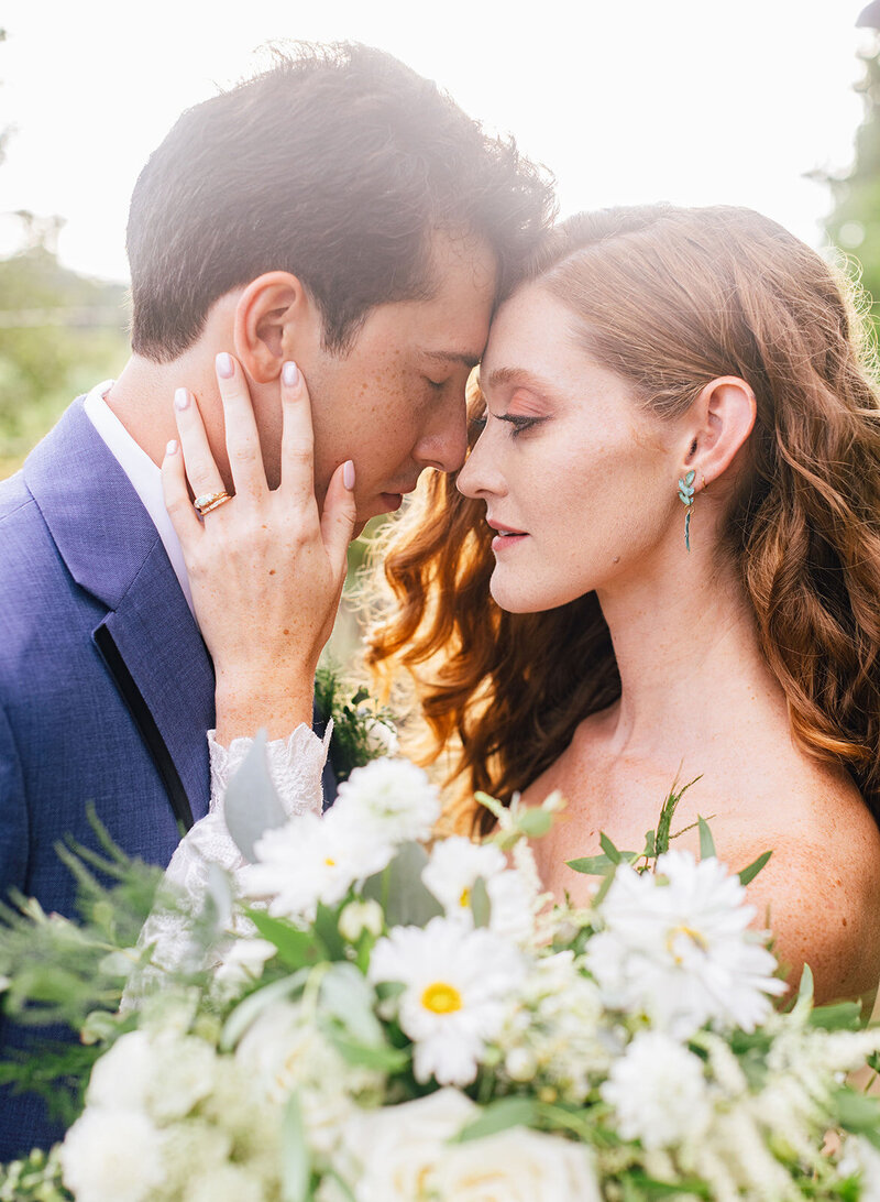 a bride and groom face to face with  a white bouquet