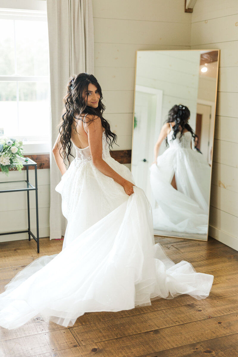 A bride in her getting ready room standing in front of the mirror twirling her dress around.