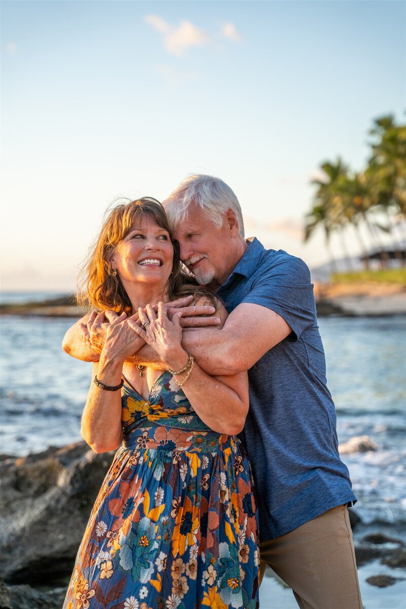 Couple smiling at each other on beach by engagement photographer in Hawaii