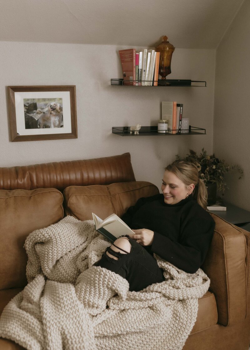 Renee Hoffman sitting on couch reading