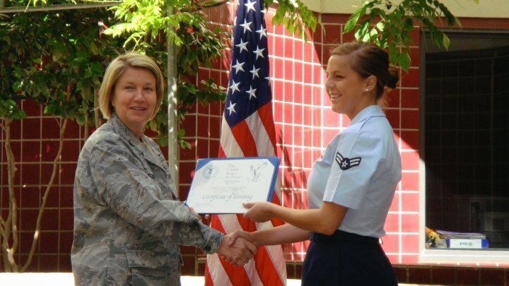 Candid photo of a Erin Marcin, Air Force veteran receiving a certificate during a military ceremony, styled with refined natural lighting and an editorial documentary approach.