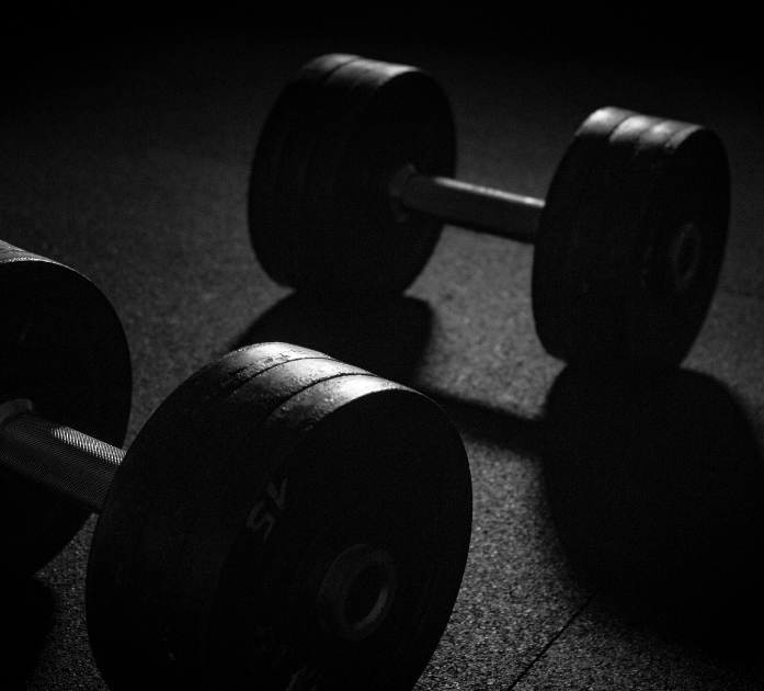 Dumbbells on gym floor representing fitness benefits of Amino Blend IV Vitamin Therapy at Refined Medical NY in East Setauket, Long Island.