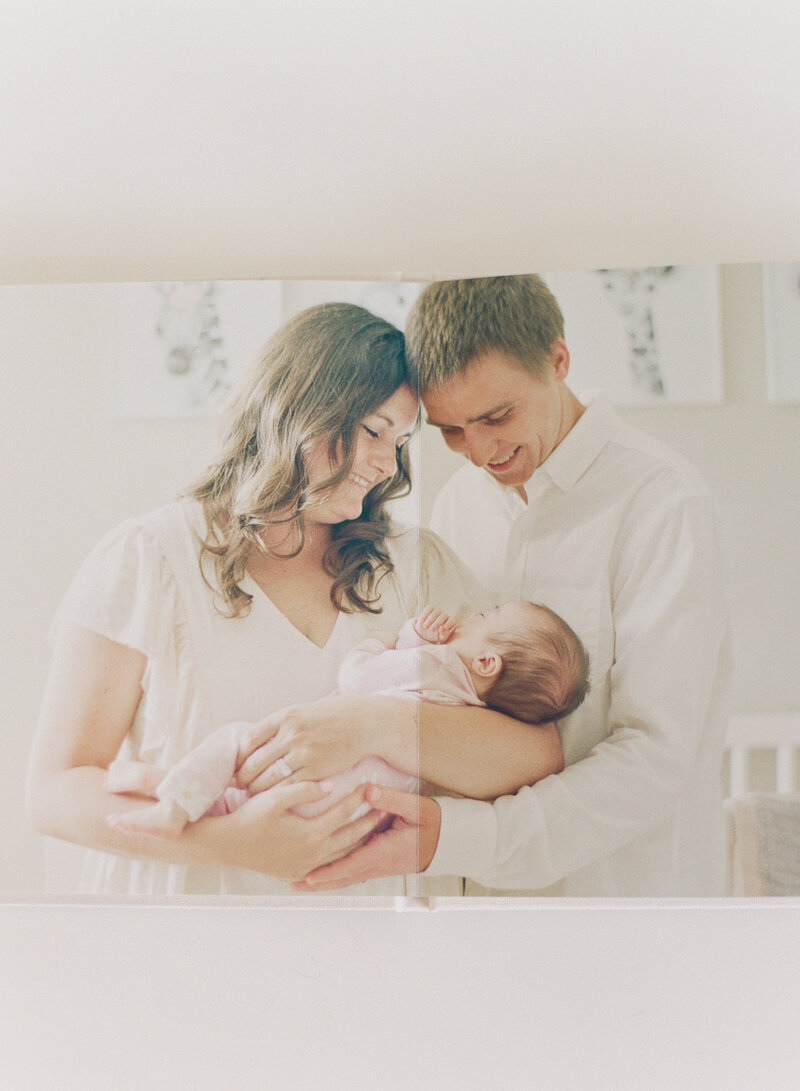 Mom and dad snuggling a new baby girl in their Raleigh newborn session. Photographed by Raleigh newborn photographers A.J. Dunlap Photography.