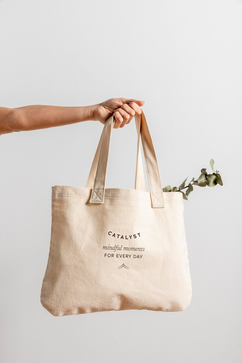 Arm holding a tote bag with the catalyst logo on it