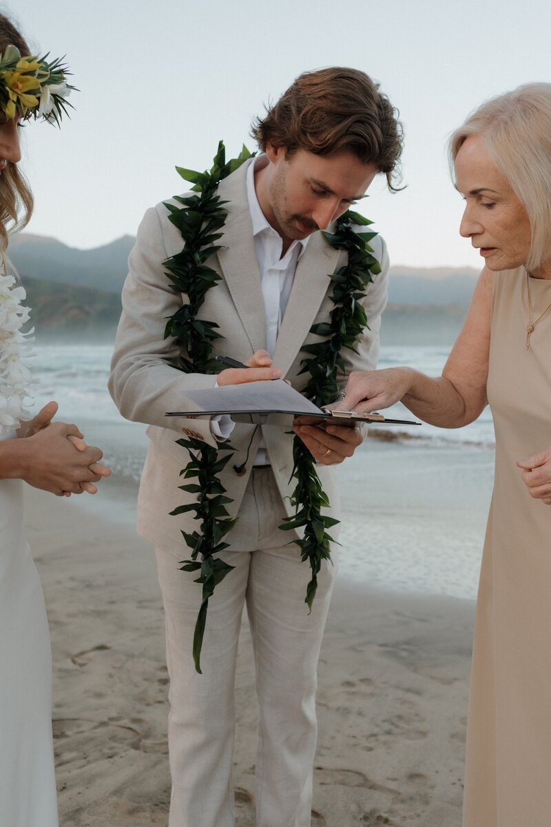 groom on beach signing marriage certificate
