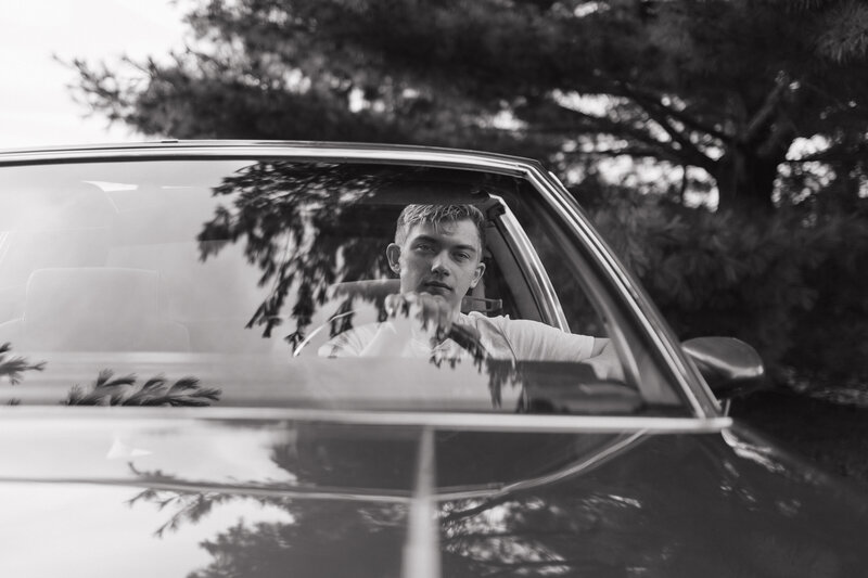young senior high school boy sitting in a vintage car