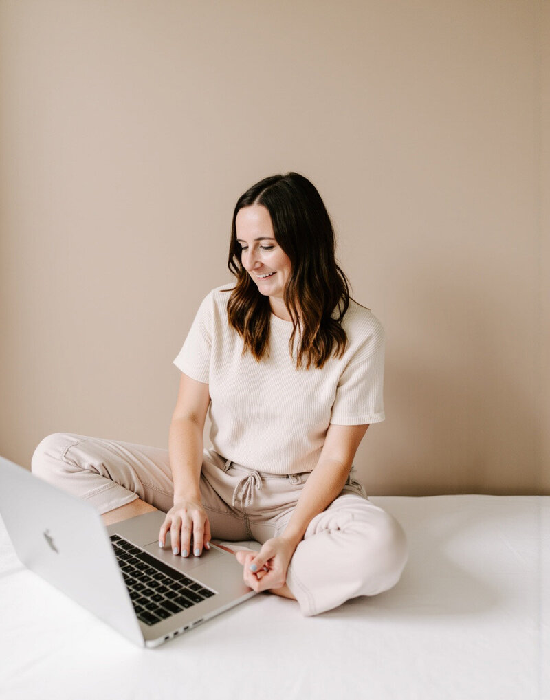 A woman sitting on the floor, focused on her laptop during a design day session.