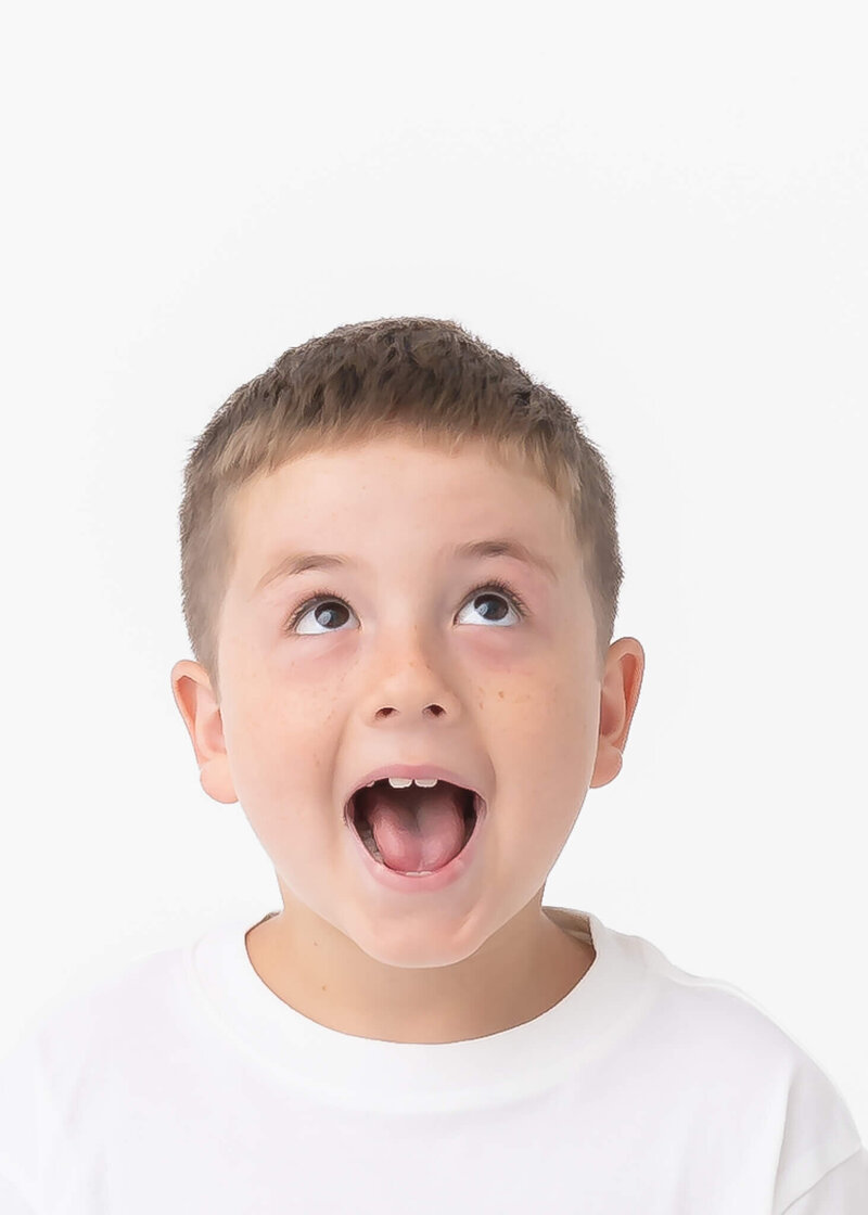 personality portrait of boy in white tee shirt on white backdrop in studio setting