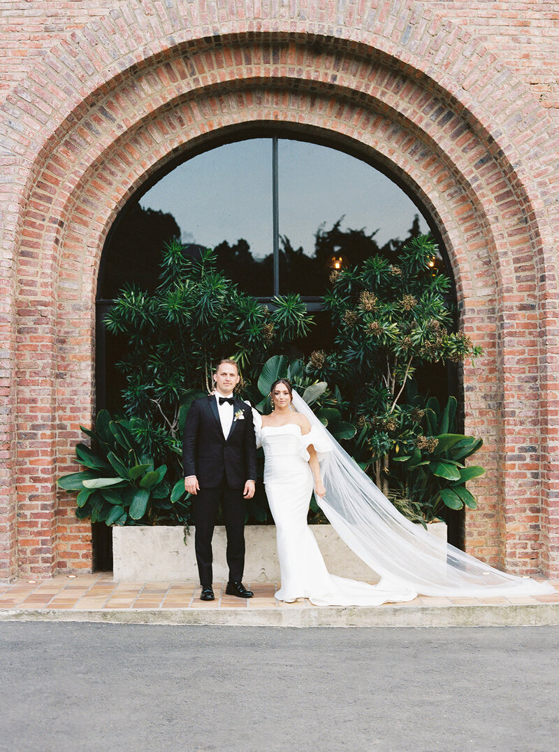 Bride and groom in the getaway car. This editorial shot has the bride standing outside of the car and the groom at the driver's seat looking up at her.