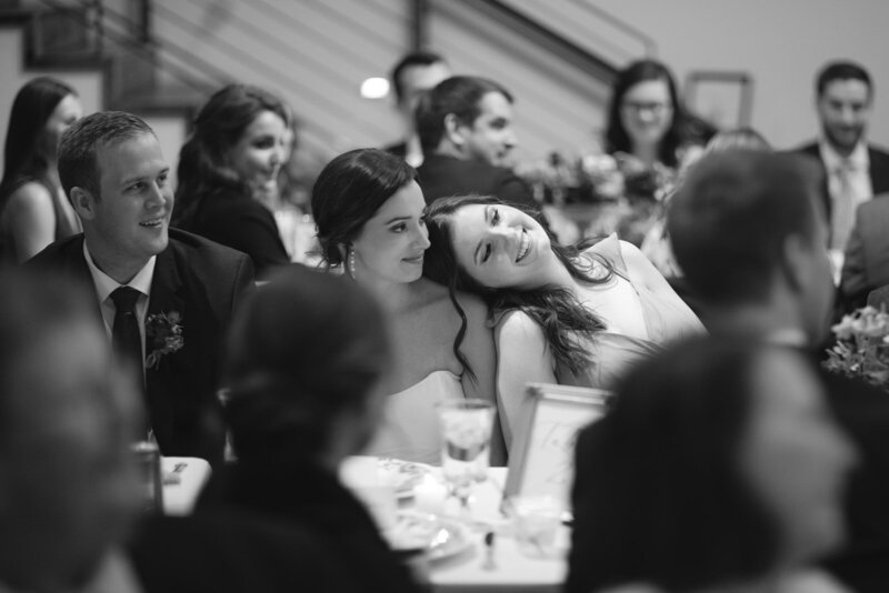 Black and white image of bride leaning on bridesmaid during Nashville wedding reception