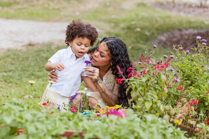 Mom shows her toddler son a purple flower