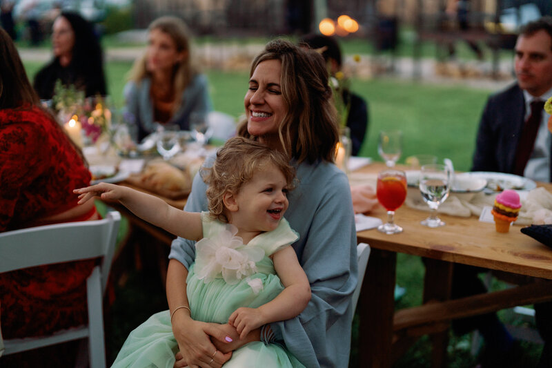 wedding guest holding baby on her lap smiling during wedding reception