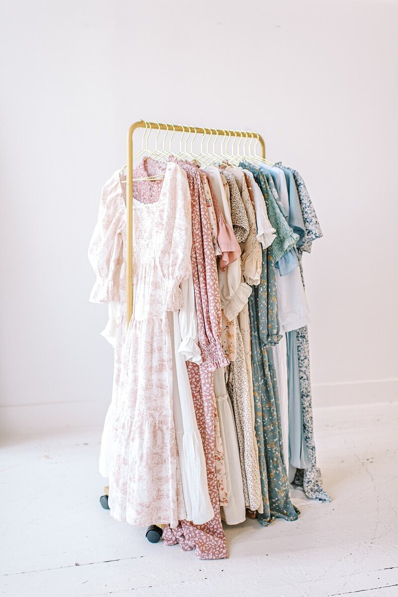 Flowy dress wardrobe options are displayed on a rack in a white studio