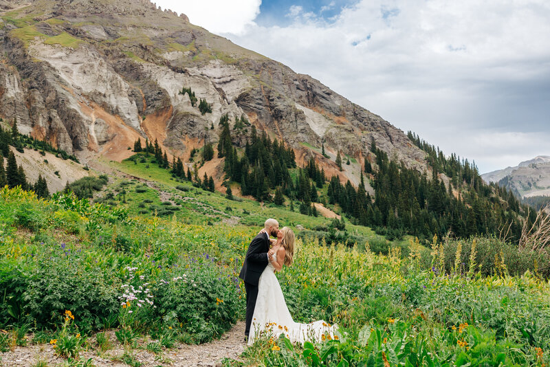 bride and groom celebrating they got married in front of mountain range with snowy peaks