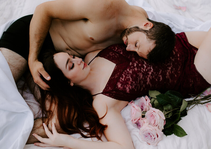 Intimate couple lying together with pink roses during their Oregon Coast elopement session.