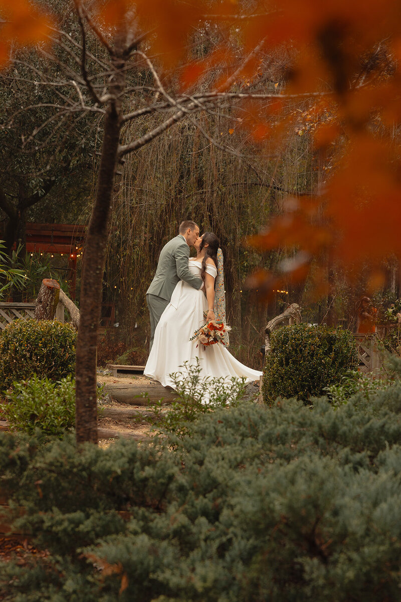 Bride and groom kissing in a garden