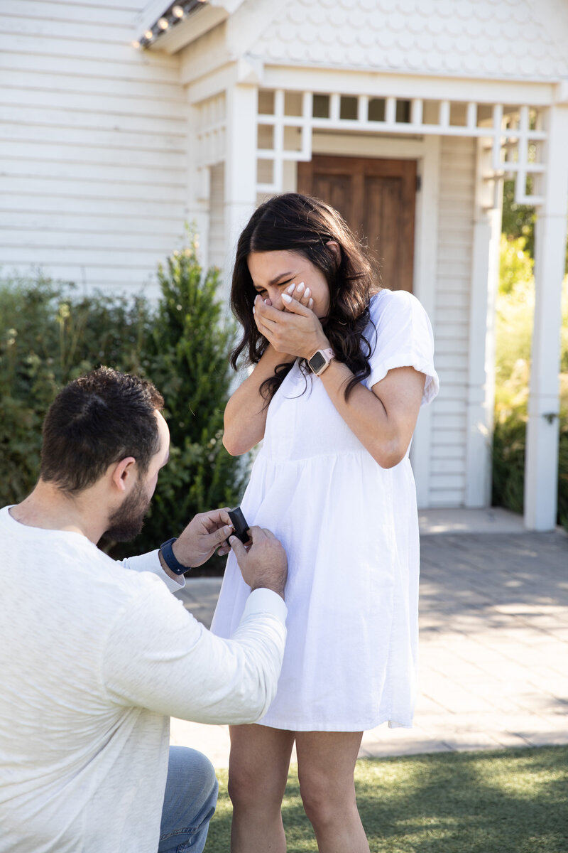An Austin wedding photographer captures a man proposing to a woman in front of a house.
