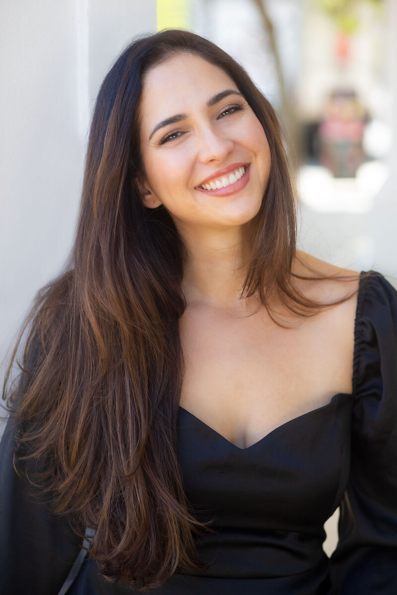 Eugenia Woo, brand a marketing coach, is looking and smiling at the camera. She's a dark-haired woman wearing a black dress.
