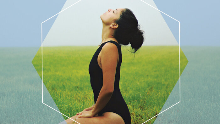 Woman meditates peacefully in grass field